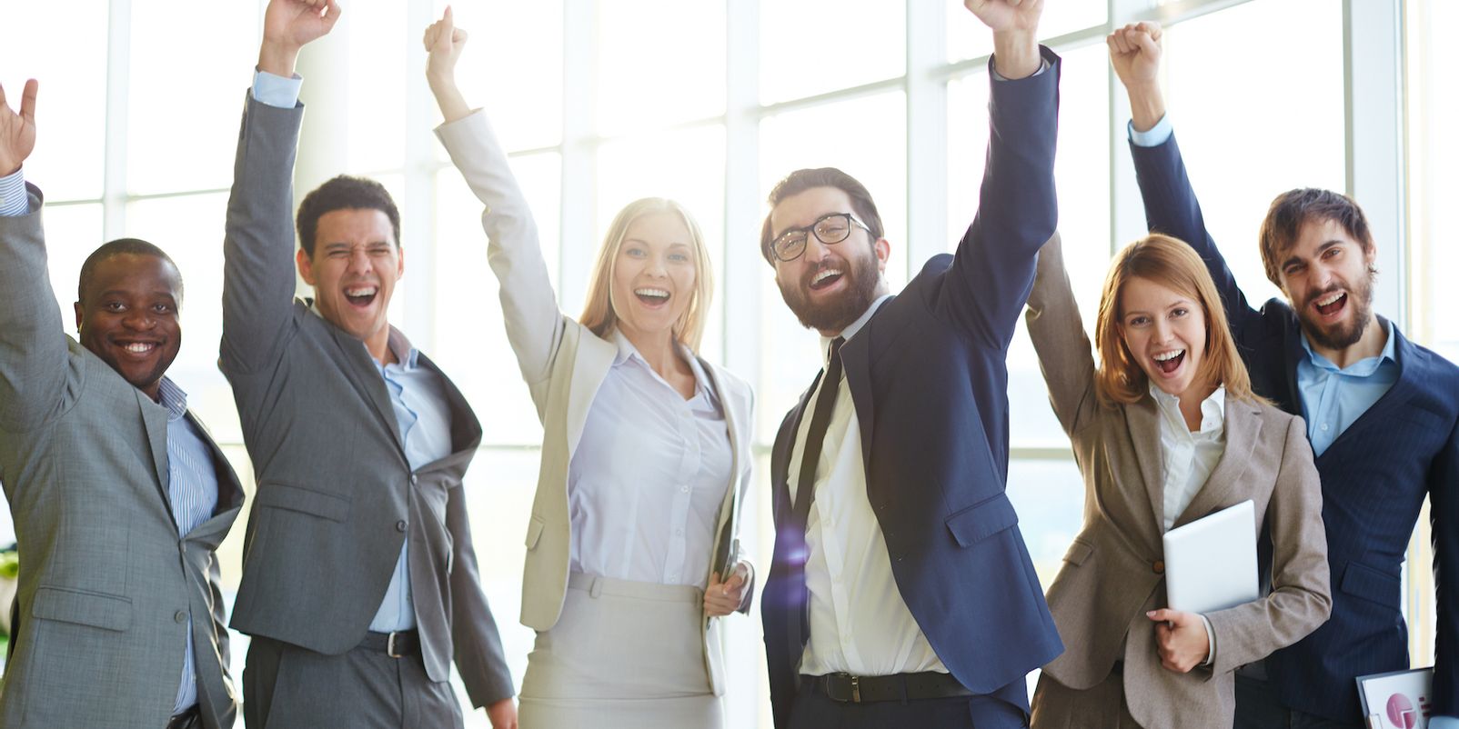 Group of ecstatic business partners looking at camera with raised arms