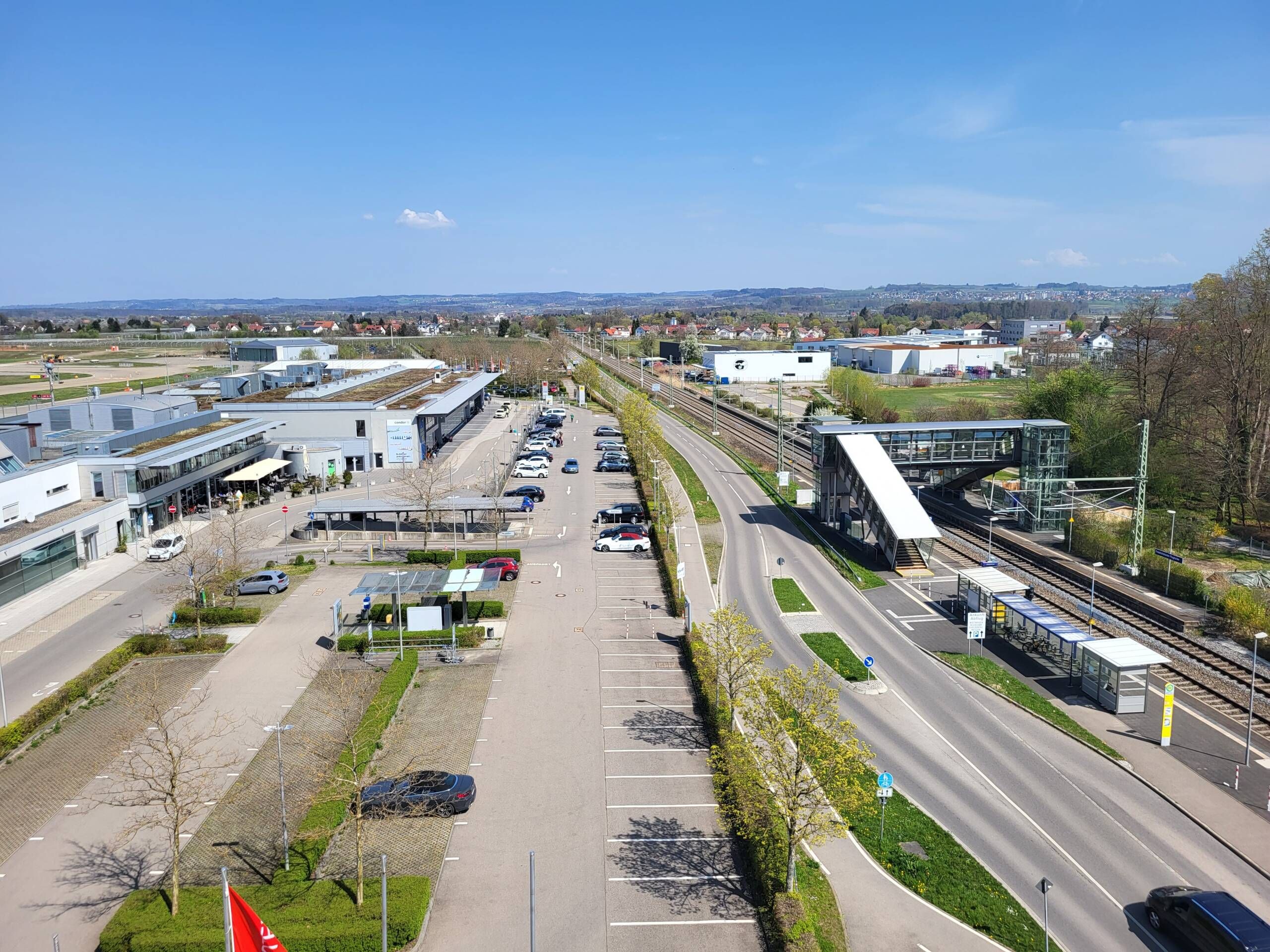 Aufnahme des Flughafen Gebäudes, der Parkplätze, der Anfahrtstraße sowie der Bahnhaltestelle von oben