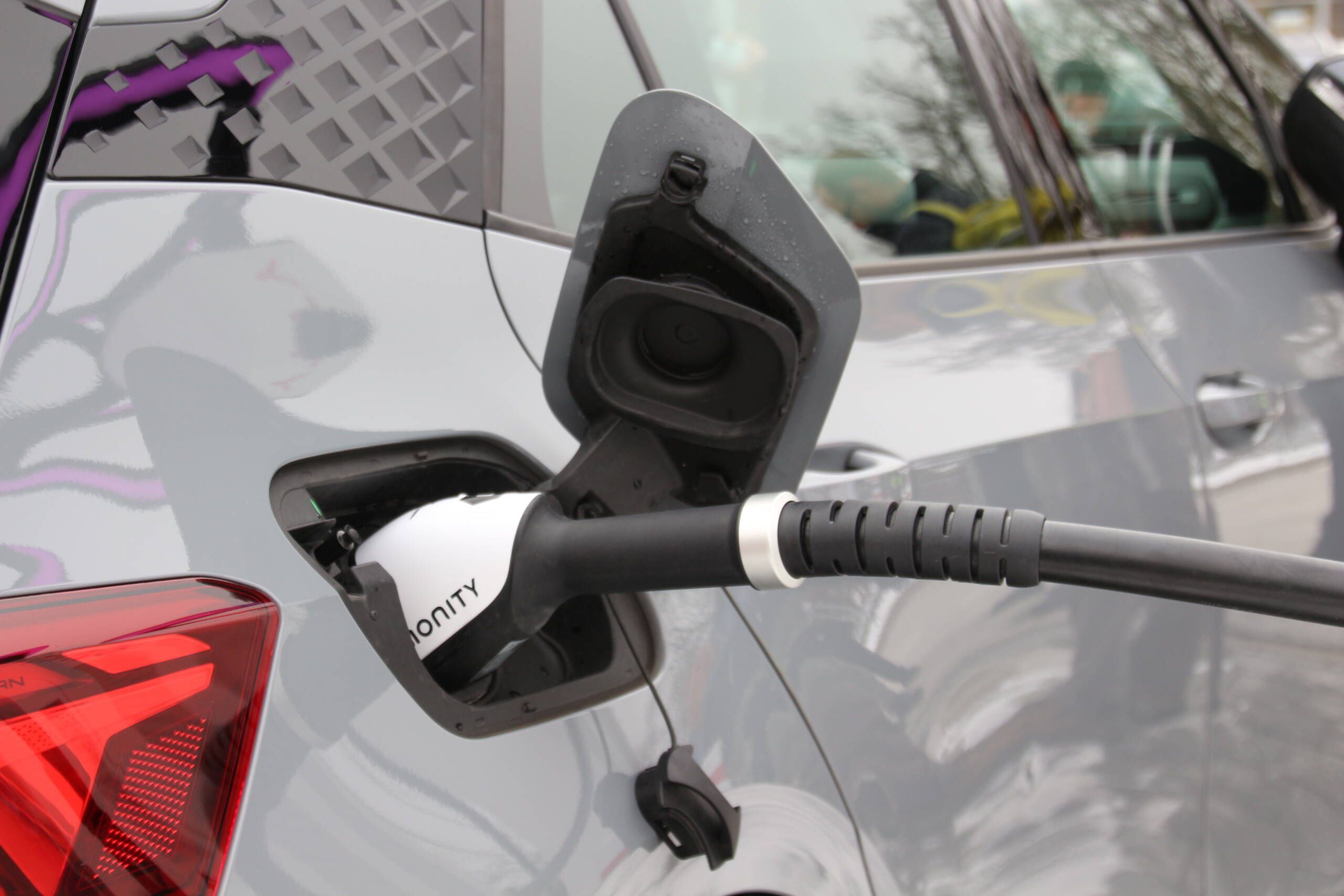 Auto mit geöffnetem Tankdeckel. Das Auto wird gerade Elektrisch aufgeladen.