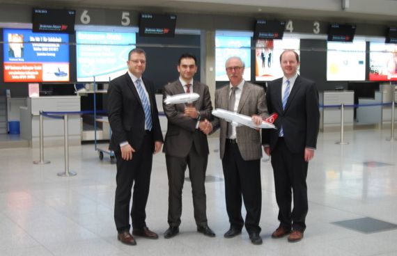 vier Männer in Anzug im Terminal des Flughafens. zwei der Männer haben ein kleines Flugzeug der Airline Turkish Airlines in der Hand