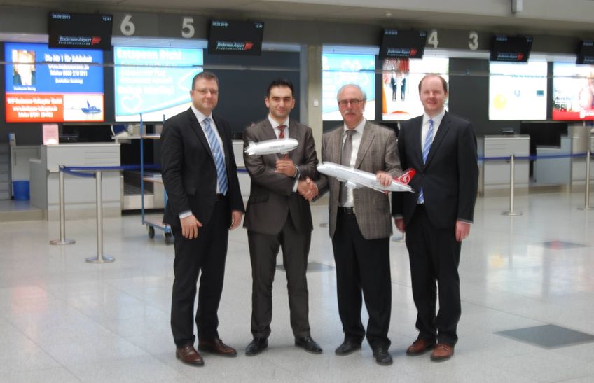 vier Männer in Anzug im Terminal des Flughafens. zwei der Männer haben ein kleines Flugzeug der Airline Turkish Airlines in der Hand
