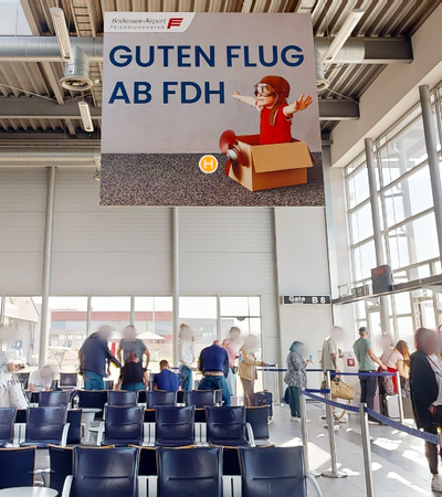 Gatebereich im Flughafen mit Werbefläche, die von der Decke hängt