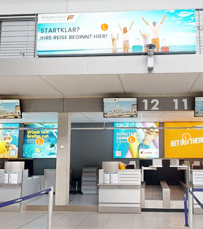 Check-In Bereich im Flughafen mit vielen Werbeflächen an der Wand