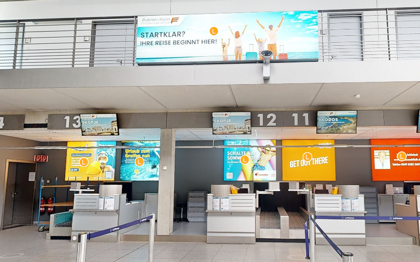 Check-In Bereich im Flughafen mit vielen Werbeflächen an der Wand