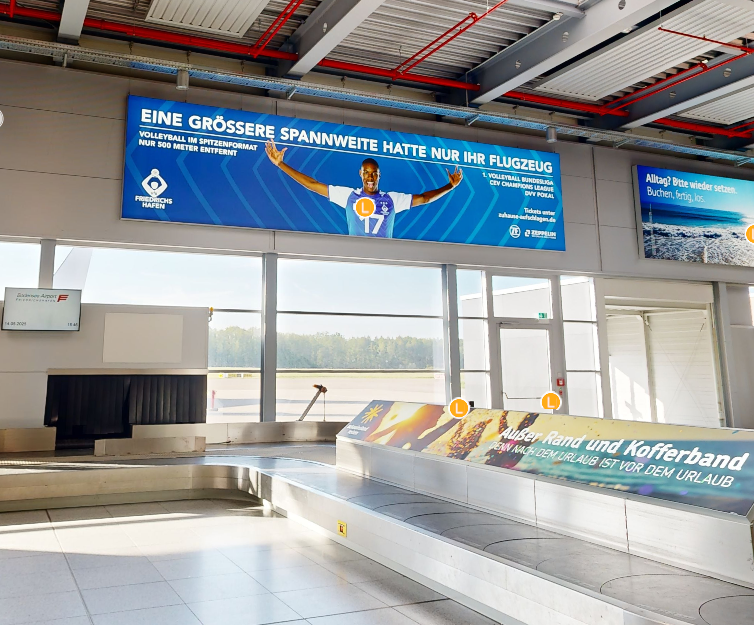 Gepäckband am Flughafen mit einem großen Werbebanner an der Wand