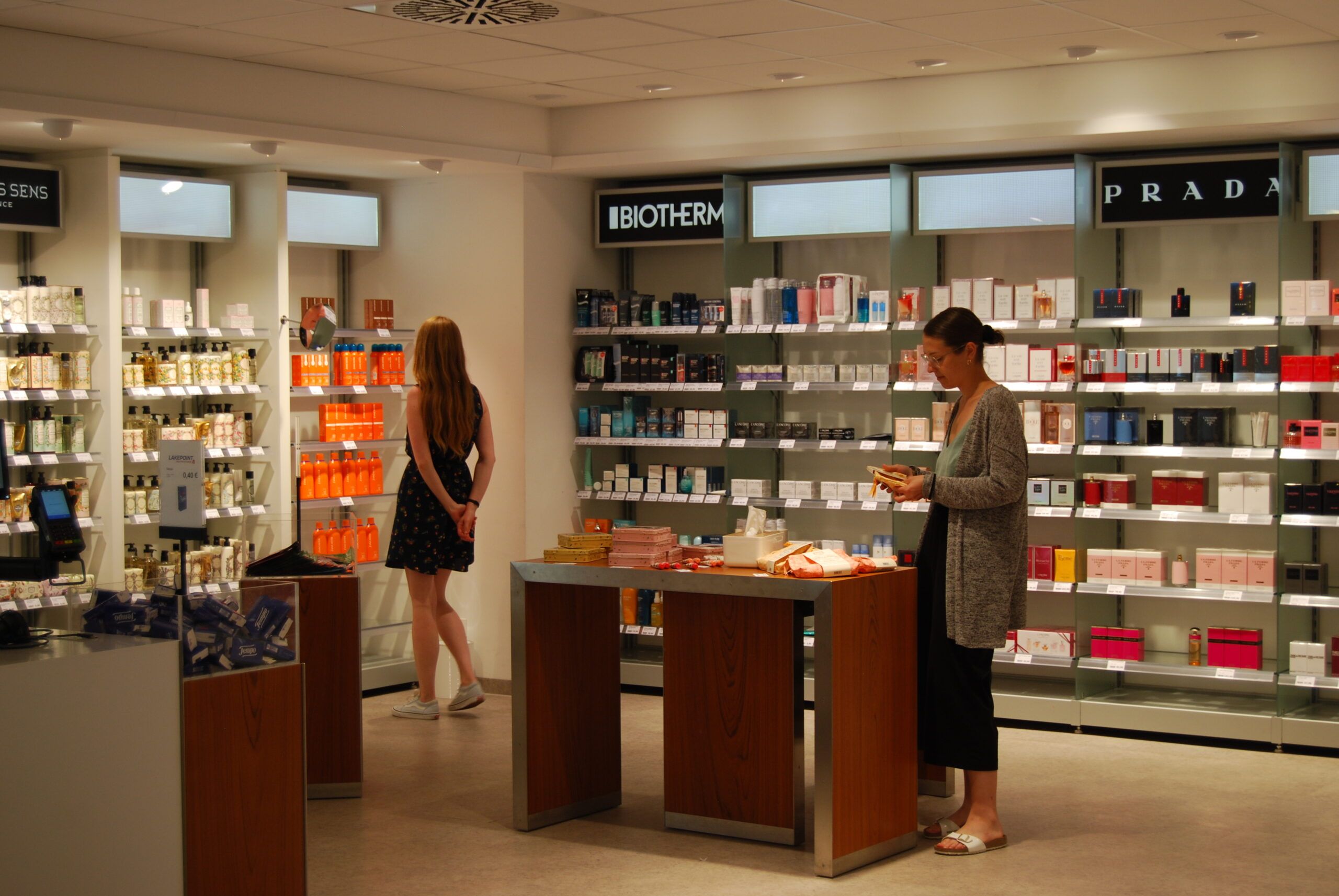 Duty Free Shop Regale und 2 Personen, die im Duty Free Shop laufen und stöbern