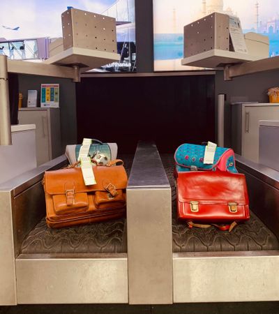 Schulranzen auf dem Gepäckband am Check-In des Flughafens