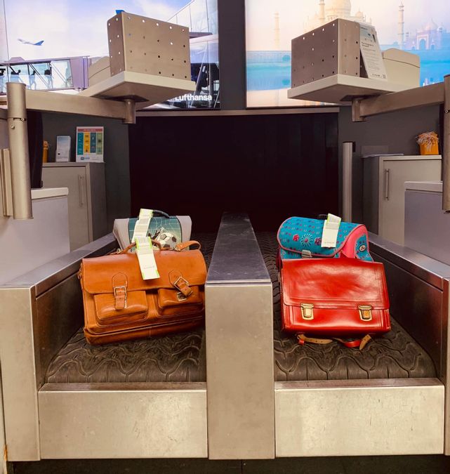 Schulranzen auf dem Gepäckband am Check-In des Flughafens