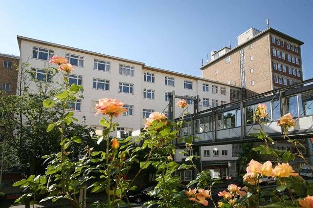 Blick auf die neurologische Klinik Westend. Vorne im Bild sind Rosen im hellen rosa zu sehen.