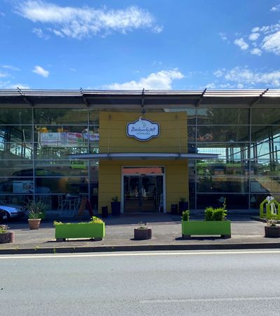 Gebäude und Eingang der Backwertstatt Schwarz bei sonnigem Wetter.