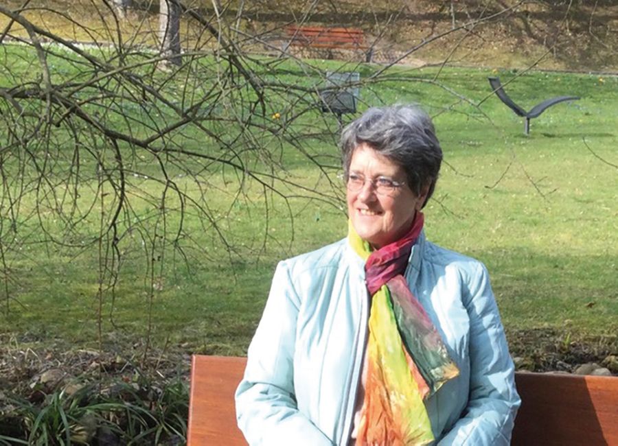 Bild der Gästeführerin Brigitte Martin auf einer Bank im Kurpark.