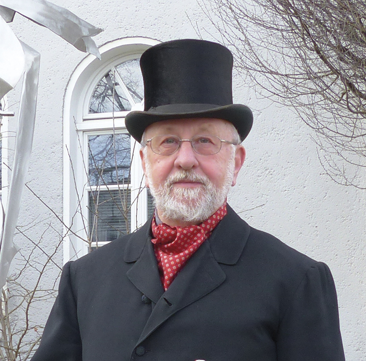 Bild des Gästeführers Gerhard Kessler im Anzug und mit einem Zylinder auf dem Kopf.