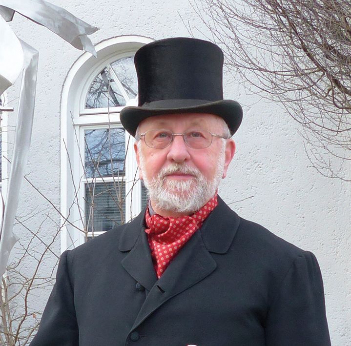 Bild des Gästeführers Gerhard Kessler im Anzug und mit einem Zylinder auf dem Kopf.