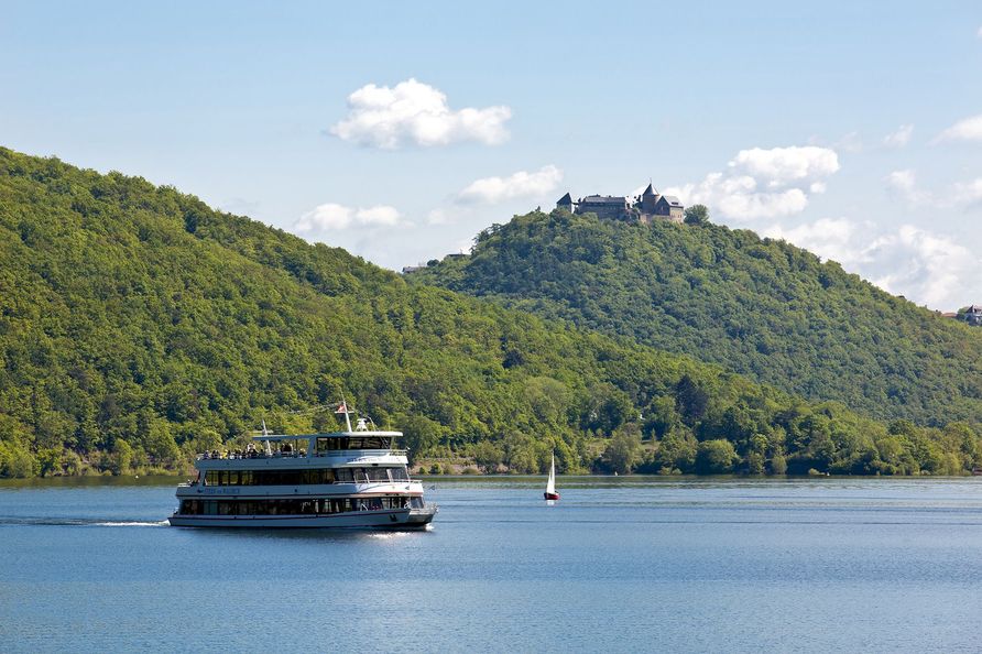 Ein Schiff fährt auf dem Edersee im Sommer und im Hintergrund thront oben das Schloss Waldeck.