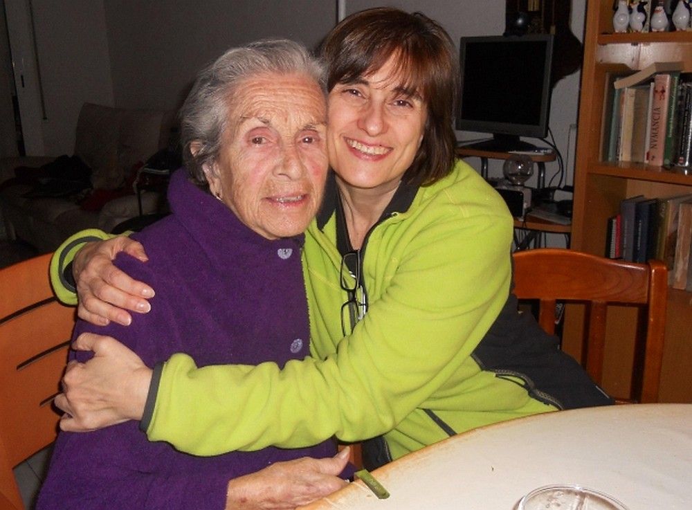 Eine ältere und eine jüngere Frau sitzen zusammen und umarmen sich.