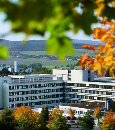 Werner Wicker Klinik Bad Wildungen-Reinhardshausen. Drumherum sind herbstliche Bäume bei sonnigem Wetter zu sehen.