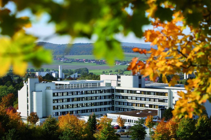 Werner Wicker Klinik Bad Wildungen-Reinhardshausen. Drumherum sind herbstliche Bäume bei sonnigem Wetter zu sehen.