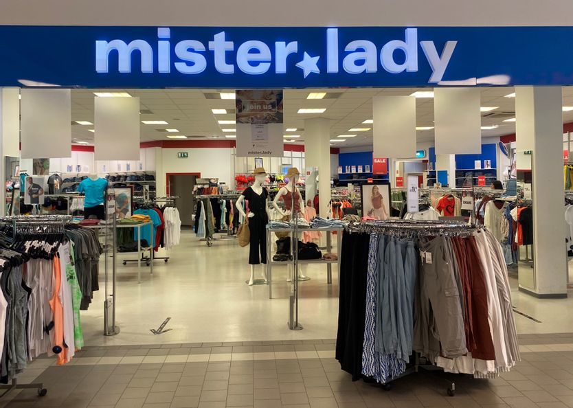 Offener Eingangsbereich von mister lady mit Blick in das Geschäft in der Fürstengalerie. Vor dem Eingang stehen Ständer mit Hosen und Shirts.