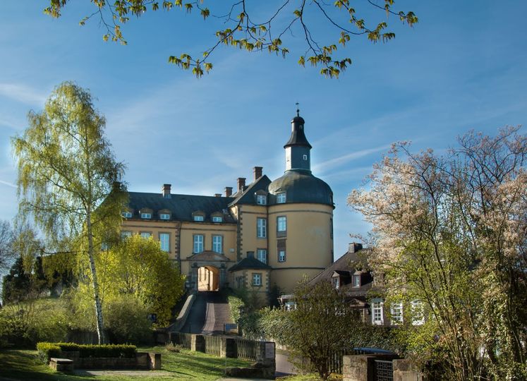 Schloss Friedrichstein Bad Wildungen bei sonnigem Wetter. Drumherum stehen blühende Bäume.