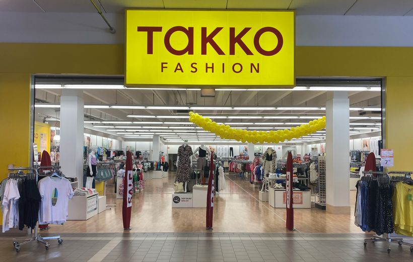 Offener Eingangsbereich von Takko Fashion mit Blick in das Geschäft in der Fürstengalerie. Rechts und links neben dem Eingang stehen Ständer mit T-Shirts.