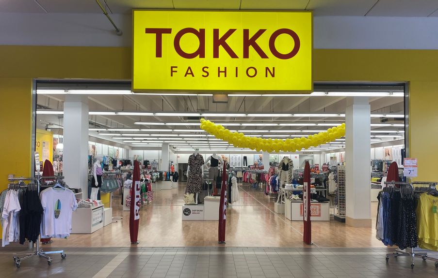 Offener Eingangsbereich von Takko Fashion mit Blick in das Geschäft in der Fürstengalerie. Rechts und links neben dem Eingang stehen Ständer mit T-Shirts.