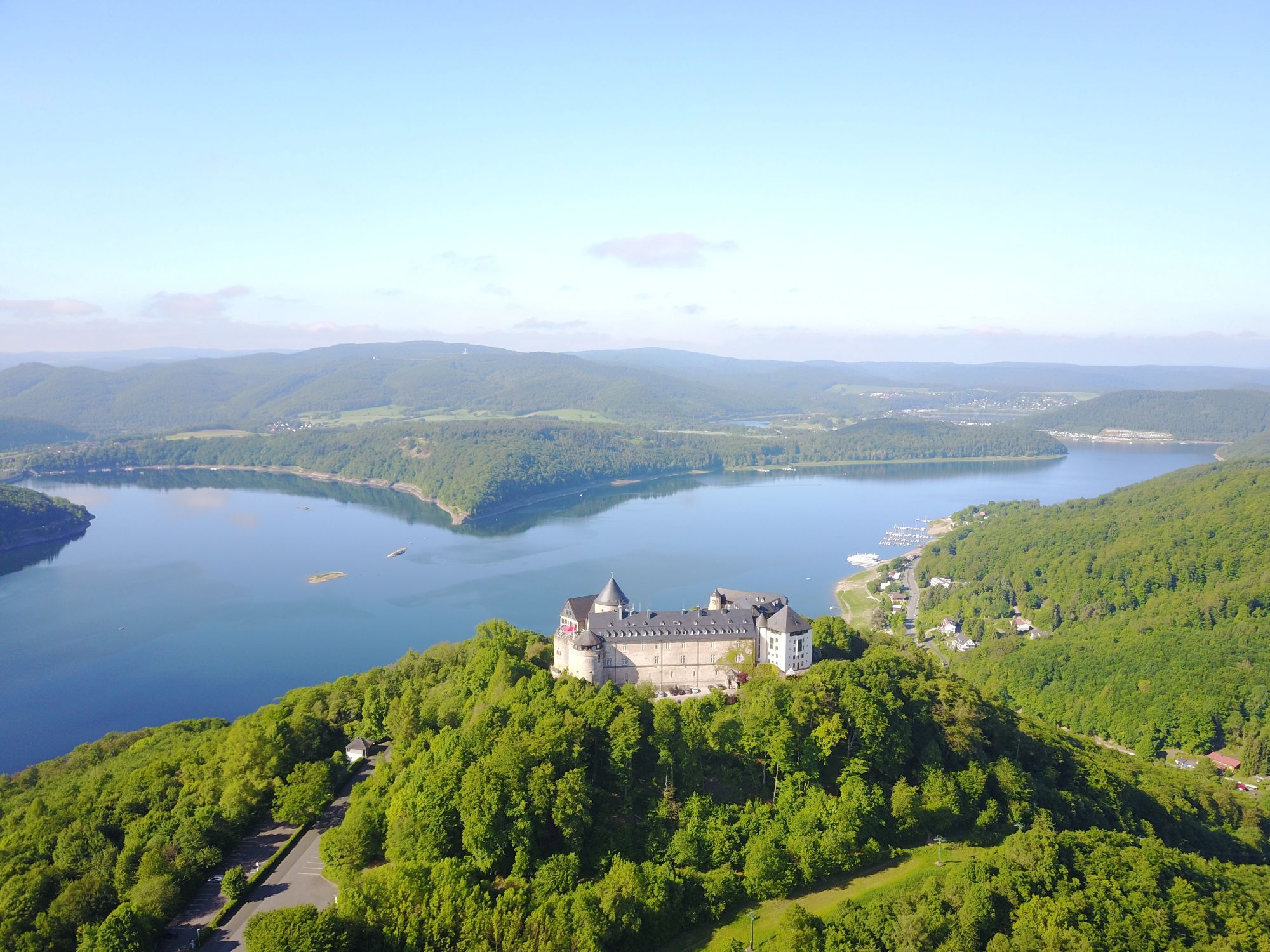 Luftbild mit dem Blick auf den Edersee und Schloss Waldeck bei Sonnenschein.