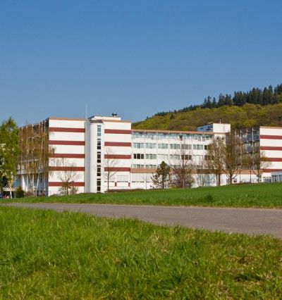 Blick auf die Klinik Hartenstein Birkental in Bad Wildungen bei sonnigem Wetter. Im Vordergrund ist eine grüne Wiese zu sehen.