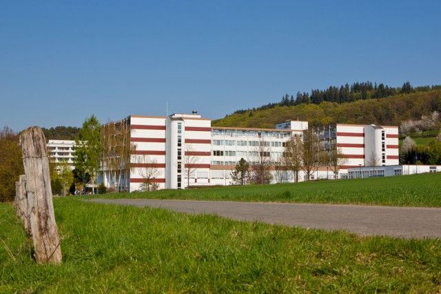 Blick auf die Klinik Hartenstein Birkental in Bad Wildungen bei sonnigem Wetter. Im Vordergrund ist eine grüne Wiese zu sehen.