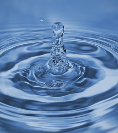 Nahaufnahme von einem Wassertropfen der ins Wasser fällt.