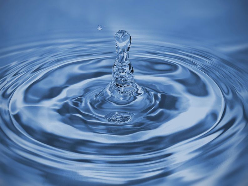 Nahaufnahme von einem Wassertropfen der ins Wasser fällt.