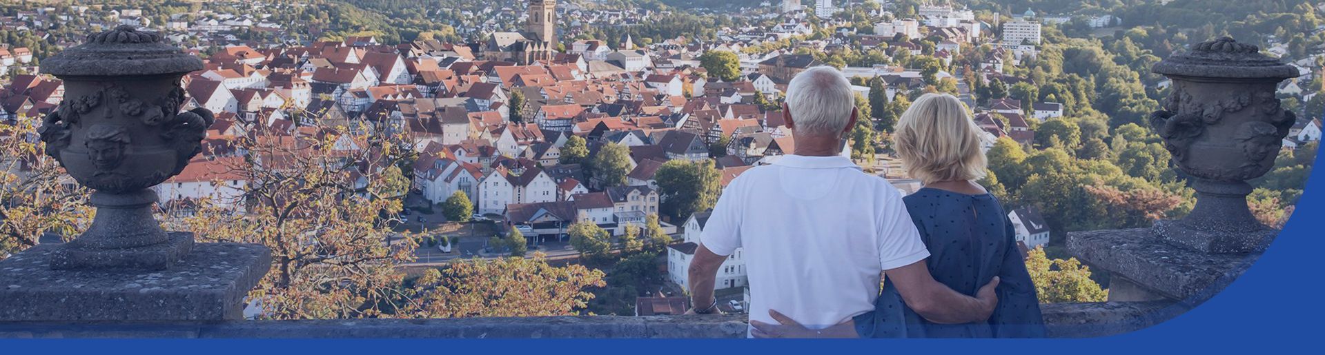 Zwei ältere Personen blicken vom Balkon des Schloss Friedrichstein auf die Bad Wildunger Altstadt