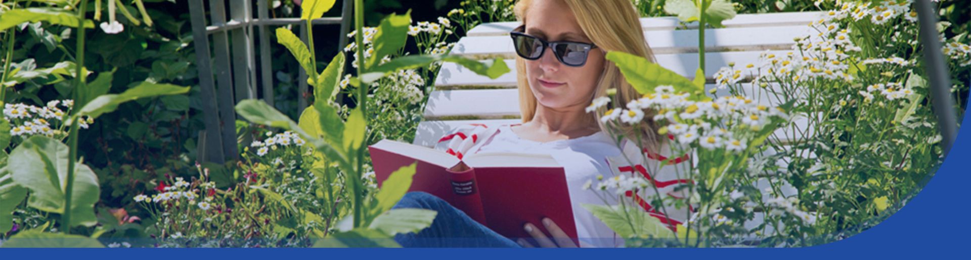 Eine Frau, die im Garten auf einer Sonnenbank ein Buch liest