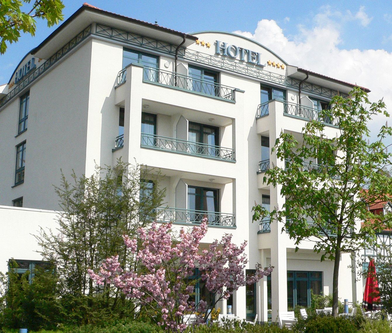 Außenansicht des Goebel's Hotel AquaVita mit blühenden Bäumen in grün und rosa.