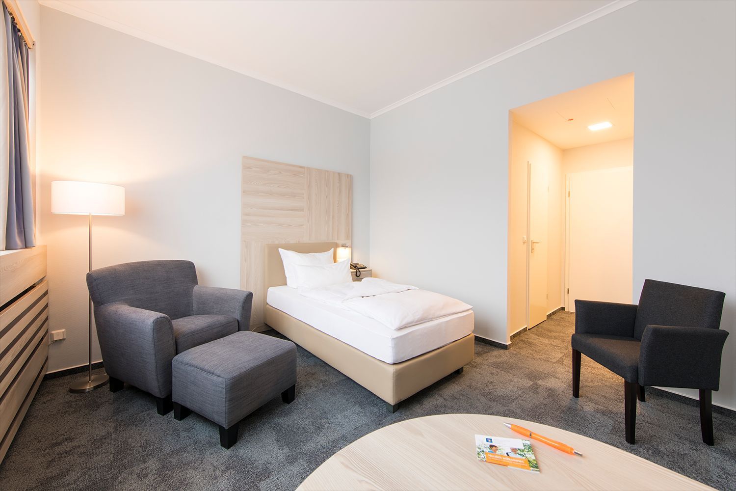 Gesundheitszentrum Helenenquelle. Blick in ein Zimmer mit Einzelbett, Zwei Sesseln und einem Tisch.