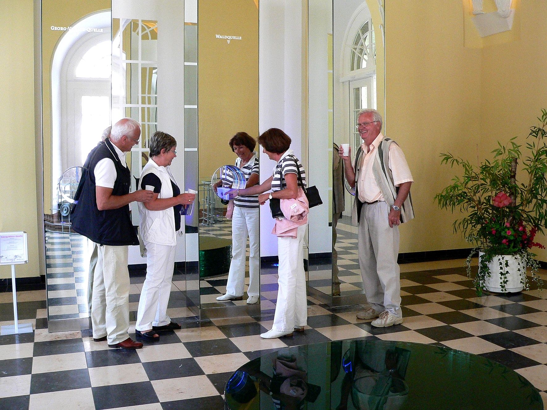 Quellendom in der Wandelhalle Bad Wildungen. Zwei Männer und zwei Frauen stehen im Quelledom vor den Zapfanlagen.