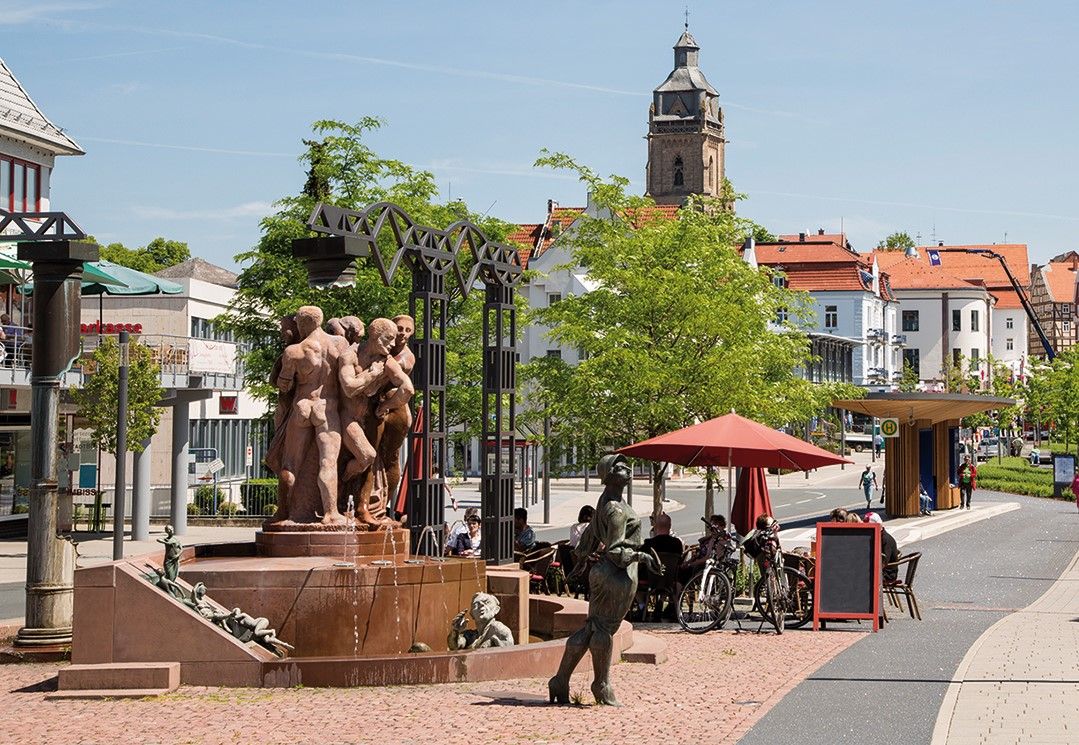 Blick auf den Kurschattenbrunnen bei sonnigem Wetter. Im Hintergrund ist die Stadtkirche zu sehen.