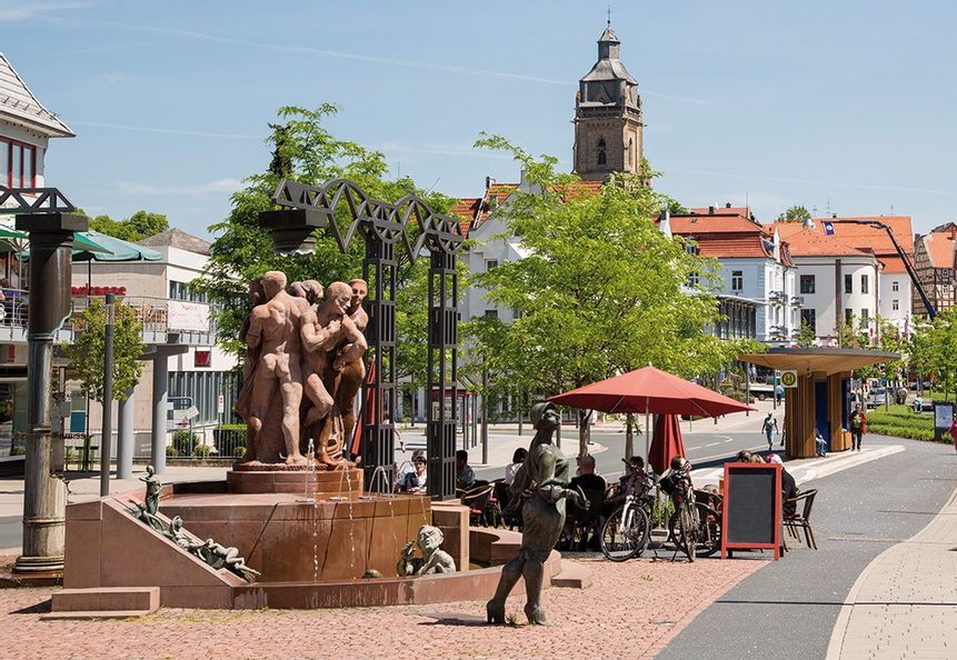 Blick auf den Kurschattenbrunnen bei sonnigem Wetter. Im Hintergrund ist die Stadtkirche zu sehen.