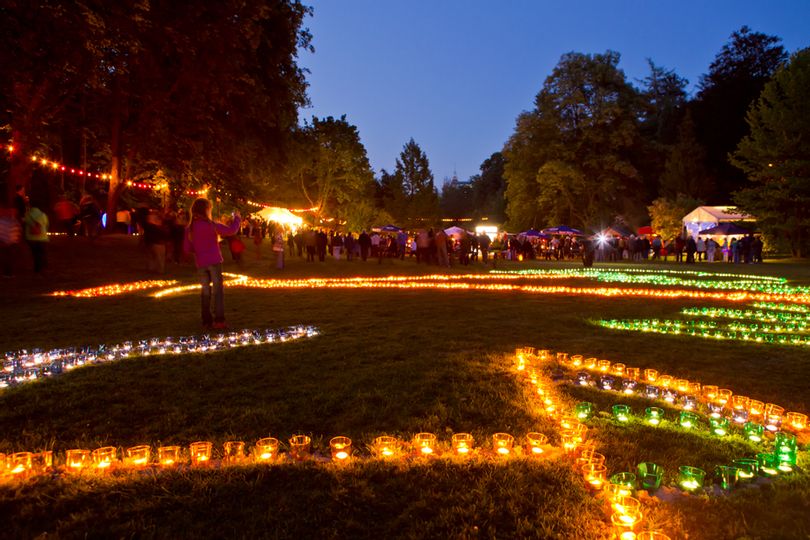 Im Vordergrund sind Kerzen auf einer Wiese im Kurpark zu sehen. Im Hintergrund sind viele Menschen und ein Teil der Tanzbühne.