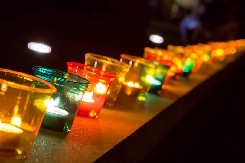 Nahaufnahme von Teelichtern in bunten Bechern.