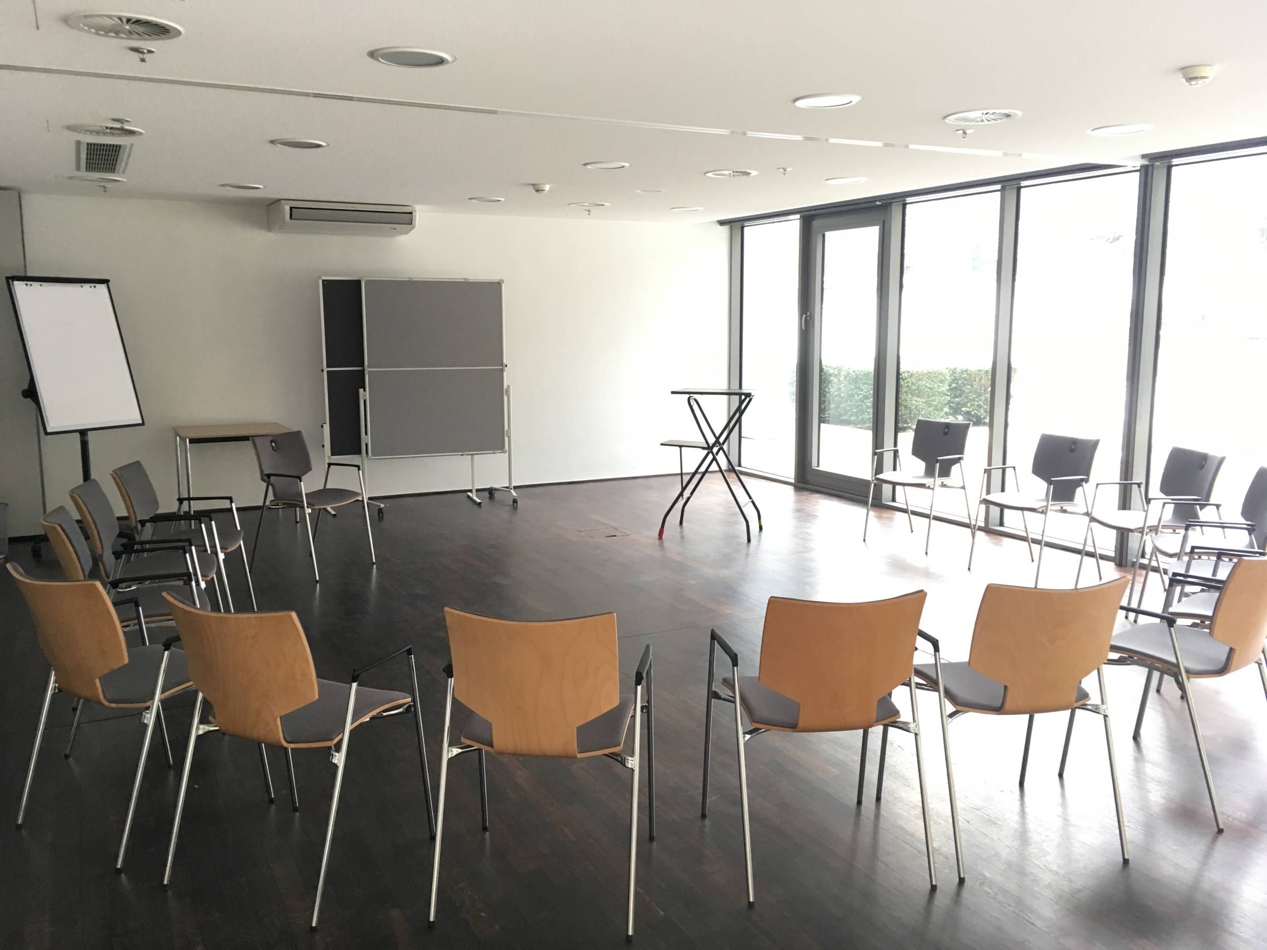 Blick in einen Seminarraum der Wandelhalle Bad Wildungen. Stühle sind in einen Stuhlkreis gestellt. Vorne steht ein Flipchart, zwei Pinnwände und ein kleiner Tisch.