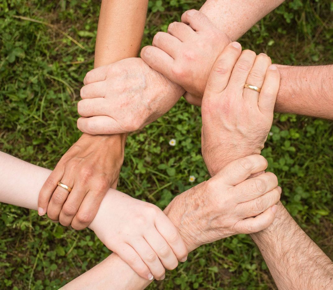 6 Personen greifen sich gegenseitig am Handgelenk so dass ein Kreis entsteht.