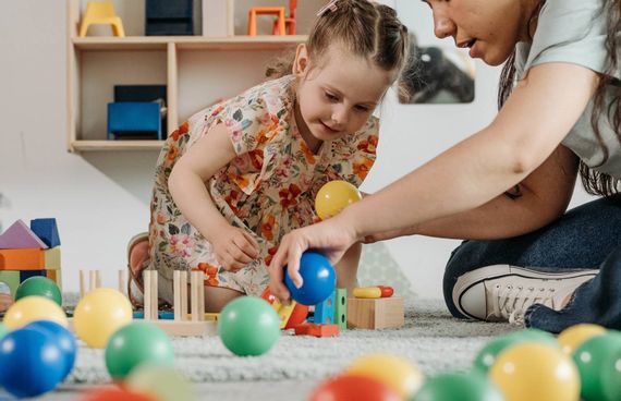 Eine Erzieherin spielt mit einem kleinen Kind.