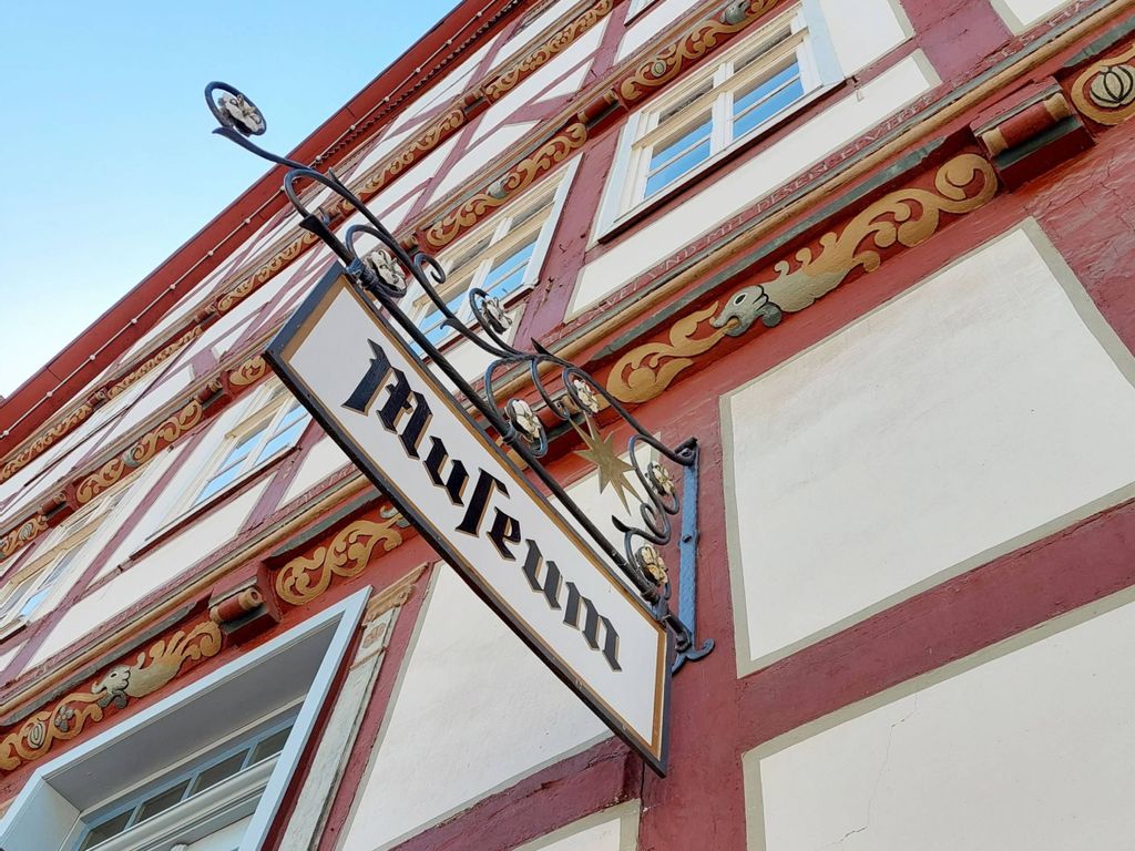 Nahaufnahme des Schildes vom Stadt Museum. Zu sehen ist eine Nahaufnahme eines roten Fachwerkhauses.
