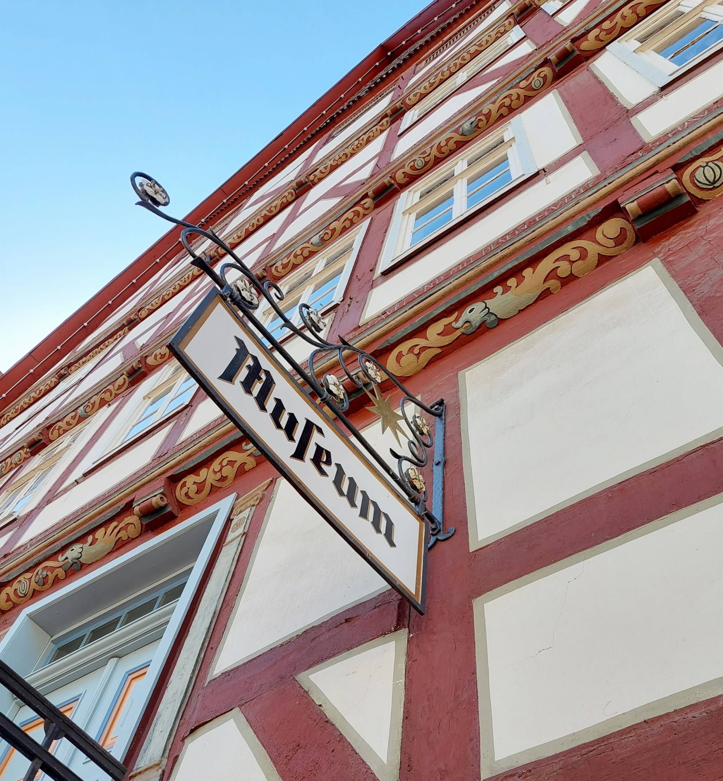 Nahaufnahme des Schildes vom Stadt Museum. Zu sehen ist eine Nahaufnahme eines roten Fachwerkhauses.