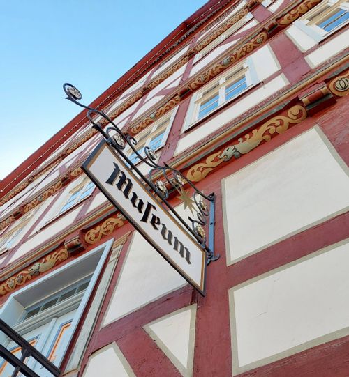 Nahaufnahme des Schildes vom Stadt Museum. Zu sehen ist eine Nahaufnahme eines roten Fachwerkhauses.