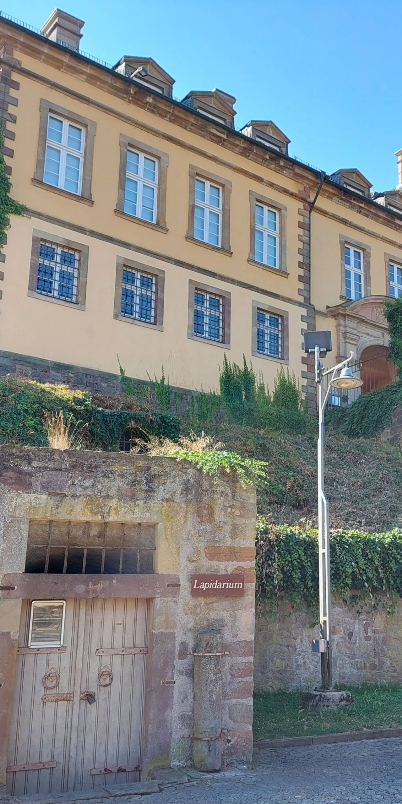 Nahaufnahme des Lapidariums unter dem Schloss Friedrichstein. Im Vordergrund ist unten links das Lapidarium zu sehen. Im Hintergrund ist Schloss Friedrichstein zu sehen.