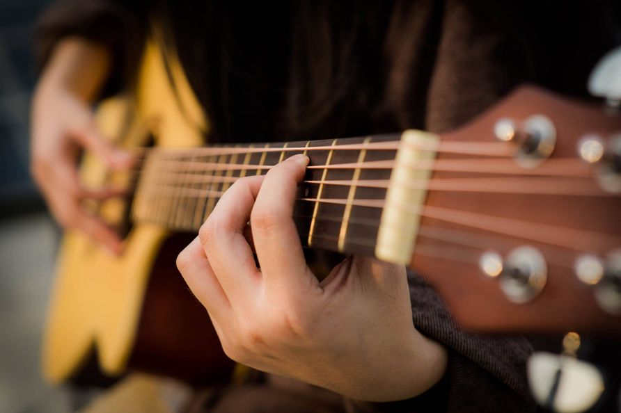Nahaufnahme einer Person die Gitarre spielt.