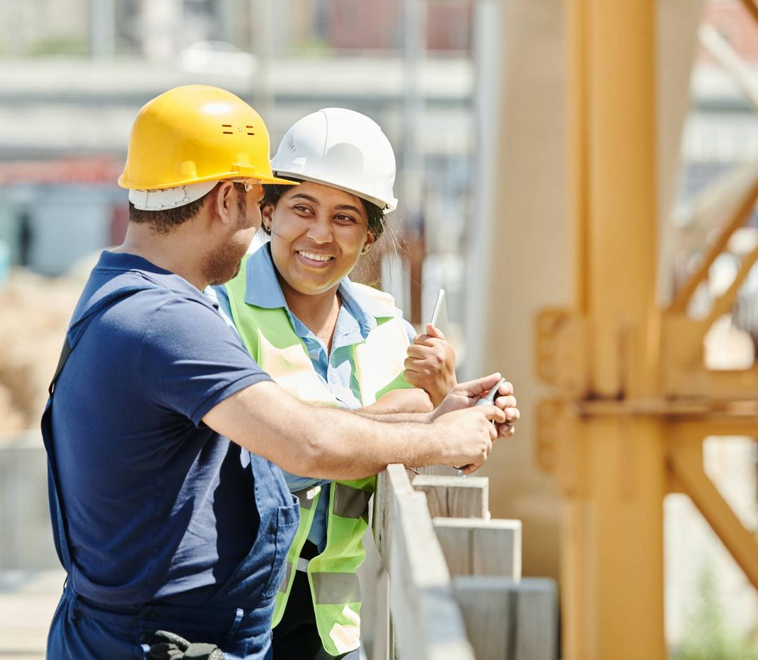 Zwei Bauarbeiter die sich auf einer Baustelle unterhalten.