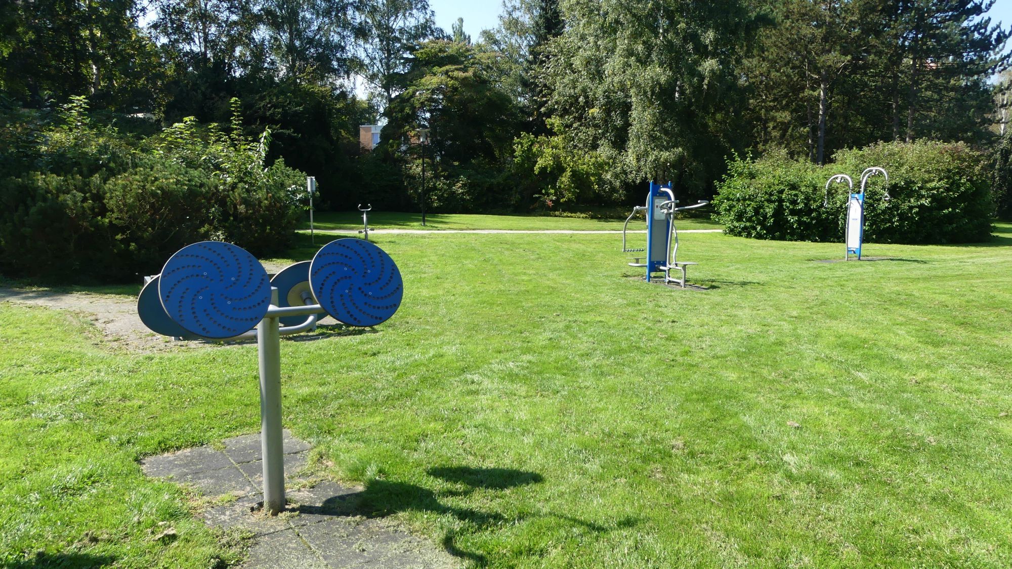 Blick auf den Outdoor-Fitnesspark auf einer Wiese im Kurpark Reinhardshausen.