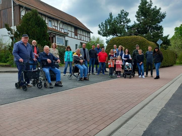 Viele Personen unterschiedlichen Alters die zusammen am Straßenrand stehen und die Kamera schauen